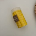 Close-up of thick yellow elastic hair ties in a clear storage jar for ponytail styling - Yellow