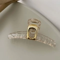 Primer plano de pinza de pelo acrílica transparente con un mecanismo de metal cuadrado dorado - Cuadrado Champán