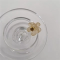 Detail van mini amberkleurige bloem haarklem met strass op een glazen rand - Champagne Bloem met Gele Strass