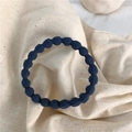 Elastisch donkerblauw golvend haarelastiekje met geweven textuur op beige stoffen basis - Donkerblauw