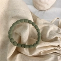Elastic dark green hair tie with bubble texture on elegant beige linen background - Bean Green