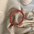 Elastic seamless hair tie in coral red with textured bubble pattern on canvas background - Pink