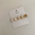 Dettaglio di cinque perle marmorizzate su un fermaglio per capelli dorato su cartoncino - Forma Rotonda / Bianco Sporco