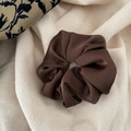 Nahaufnahme eines braunen Satin-Haargummis mit glatter Textur und edlen Falten-Details - Dunkelbraun