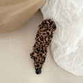 Primer plano de pinza banana en tela de leopardo con elegantes pliegues sobre fondo beige - Pinza Banana Tela Plisada Leopardo / Estampado de leopardo
