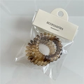 Dettaglio di elastico a spirale ambra leopardato in confezione singola con cartellino bianco - Beige