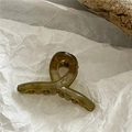 Detailed macro view of an amber translucent hair claw clip with cross-twist design - Fruit Green (Mini Cross)