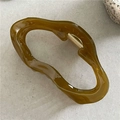 Dettaglio ravvicinato della molletta per capelli in resina ambra scura con molla dorata - Nuvola Verde Giallo