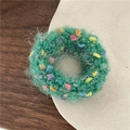 Close-up of green plush knit hair scrunchie with colorful spots on a rustic wooden desk - Green Gradient