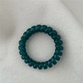 Close-up of a dark teal translucent spiral telephone cord hair tie on felt background - Teal