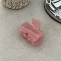 Detail of pink acetate bow hair clip with gold lettering on a grey textured surface - Bow Claw Clip / Light Pink