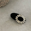 Macro shot of oval gold zircon hair clip featuring rectangular stones on black velvet base - Black Oval