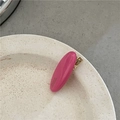 Detalle de una pinza para el pelo ovalada rosa brillante con base dorada en plato blanco - Rosa Roja