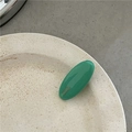 Primer plano de una pinza para el cabello ovalada verde brillante en un plato de cerámica - Verde Menta