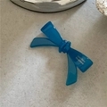 Detailed top view of a dark blue acetate bow hair clip with white brand lettering - Teal