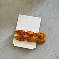 Detailed macro view of two amber acetate twist hair clips on white display card - Twisted Clips / Brown