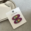 Détail de barrettes ovales mauves avec strass verts et jaunes sur carte de support - Paire violette