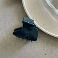 Dettaglio di una molletta per capelli verde scuro fatta a mano con scritte dorate su superficie liscia - Blu navy