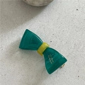 Detailed macro of a green and yellow resin bow hair clip with polished finish - Teal