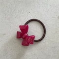 Detail of a bright pink acetate bow hair tie with high-elastic dark brown rope texture - 3D Bow / Red