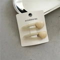 Primer plano de horquillas de corazón de resina beige en tarjeta sobre fondo grisáceo - Blanco Roto
