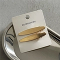 Detail von zwei gebürsteten goldenen Haarklammern auf einer minimalistischen Karte - Goldene Paar-Klammern