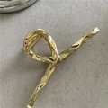 Dettaglio di una pinza per capelli in lega dorata lucida con un design a torsione di lusso - Oro Lucido