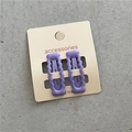 Dettaglio di due fermagli per capelli rettangolari ondulati viola in metallo su carta - Viola