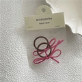 Détail d'un lot de deux chouchous faits main avec nœuds en daim rose sur fond blanc texturé - Rose Rouge
