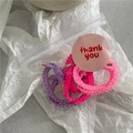Gros plan sur des chouchous en tissu volanté violet et rose dans un sachet avec étiquette - Rose Rose Violet