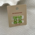 Close-up of two green polka dot hair clips on a professional display card for retail - Green