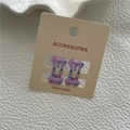 Close-up of two purple bone-shaped hair clips with colorful polka dots on card - Purple