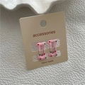 Détail de barrettes à cheveux roses en forme d'os avec des pois colorés sur carte - Rose