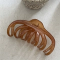 Macro-detail van de amberkleurige haarklem met gouden metalen veer en gepolijste finish - Lichtkoffie