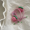 Close-up of pink elastic hair ties with strawberry pendants on a white paper background - Strawberry Style