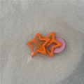 Primer plano de dos pinzas para el cabello naranja en forma de estrella con acabado mate - Naranja