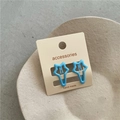 Close-up of a pair of bright blue star-shaped metal hair clips on display card - A3.2 Light Sky Blue (pentagram Clip) Jx-b187