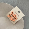 Close-up of peach butterfly hair clips on accessory card with ceramic plate background - Orange