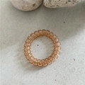 Détail d'un élastique spirale ambre translucide sur un fond en pierre minimaliste - Marron