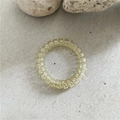 Détail d'un élastique spirale jaune translucide sur un fond de pierre minimaliste - Beige