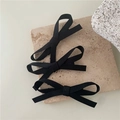 Detalle de tres pinzas para el cabello con lazo negro sobre superficie de piedra pura - Negro