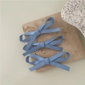 Primer plano de tres clips de pelo con lazos azules sobre una base de piedra - Azul