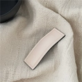 Detail shot of a cream-colored PU leather rectangular hair clip with neat stitching - Off White