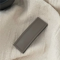Detailed view of a taupe PU leather rectangular hair clip with fine stitching on knit fabric - Gray