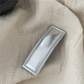Detail einer silbernen rechteckigen Kunstleder-Haarspange mit Perlenrand auf beige Strick - Silber
