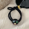 Dettaglio dell'elastico per capelli nero con perlina a forma di clown e punte in metallo oro - Nero