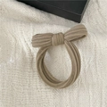 Detailed close-up of a beige bow hair scrunchie with soft velvet towel texture on fabric - Khaki