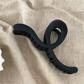 Detail of matte black minimalist geometric hair claw clip on beige fabric background - Wave Cross Claw Clip / Black