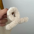 Close-up of beige plush hair claw clip made of soft lamb wool with metal spring - Off White