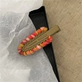 Dettaglio di un fermaglio per capelli in lana colorata fatto a mano con fili rosa e arancio - Marrone chiaro